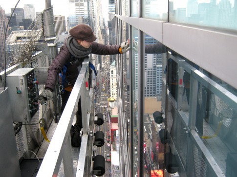 Like a seasoned pro, Maria Arutunyan inspects the facade with one hand while operating the scaffold with the other. 