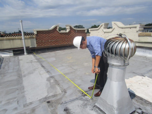 Taking measurements for a roof replacement and repair project at an Inwood apartment building.