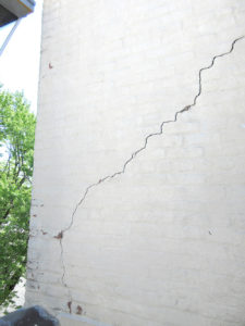 Diagonal and vertical cracks observed in the building’s parapet walls prompted the need for emergency repairs.