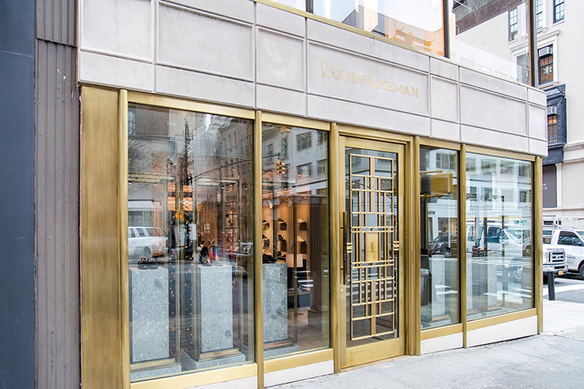 <p>Custom storefront including engraved limestone sign band, granite stone bulkhead cladding, tempered glass, and aged brass metalwork door and framing caps.</p>
