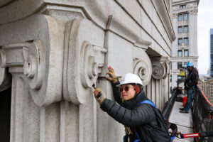 Close-up, hands-on inspection of ornate stone facade elements during a FISP inspection in New York City.