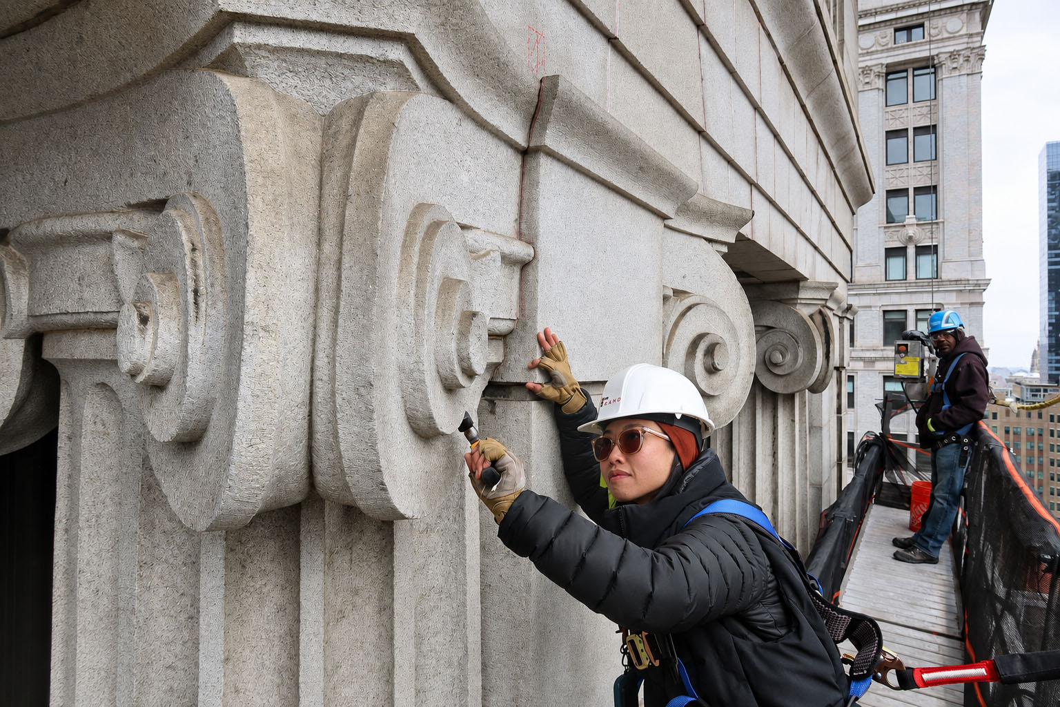 Close-up, hands-on inspection of ornate stone facade elements during a FISP inspection in New York City.